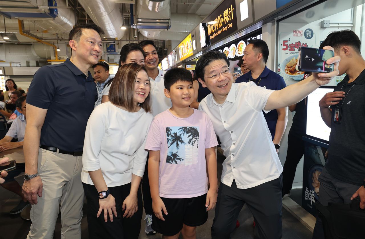 When Prime Minister Wong Xuncai (who holds a cell phone) visited Sengkang area, he took a photo with residents. Standing next to him were Lan Binming (first from left) and Li Xiyi (half-squat), a consultant to the grassroots organization of Sengkang GmbH constituency. Behind Li Xiyi is Wang Shijia (Banzhe), chairman of the Sengkang East Branch, and Elmi, another consultant to the grassroots organization of the Sengkang Group Constituency. (Photo by Wu Fuliang)